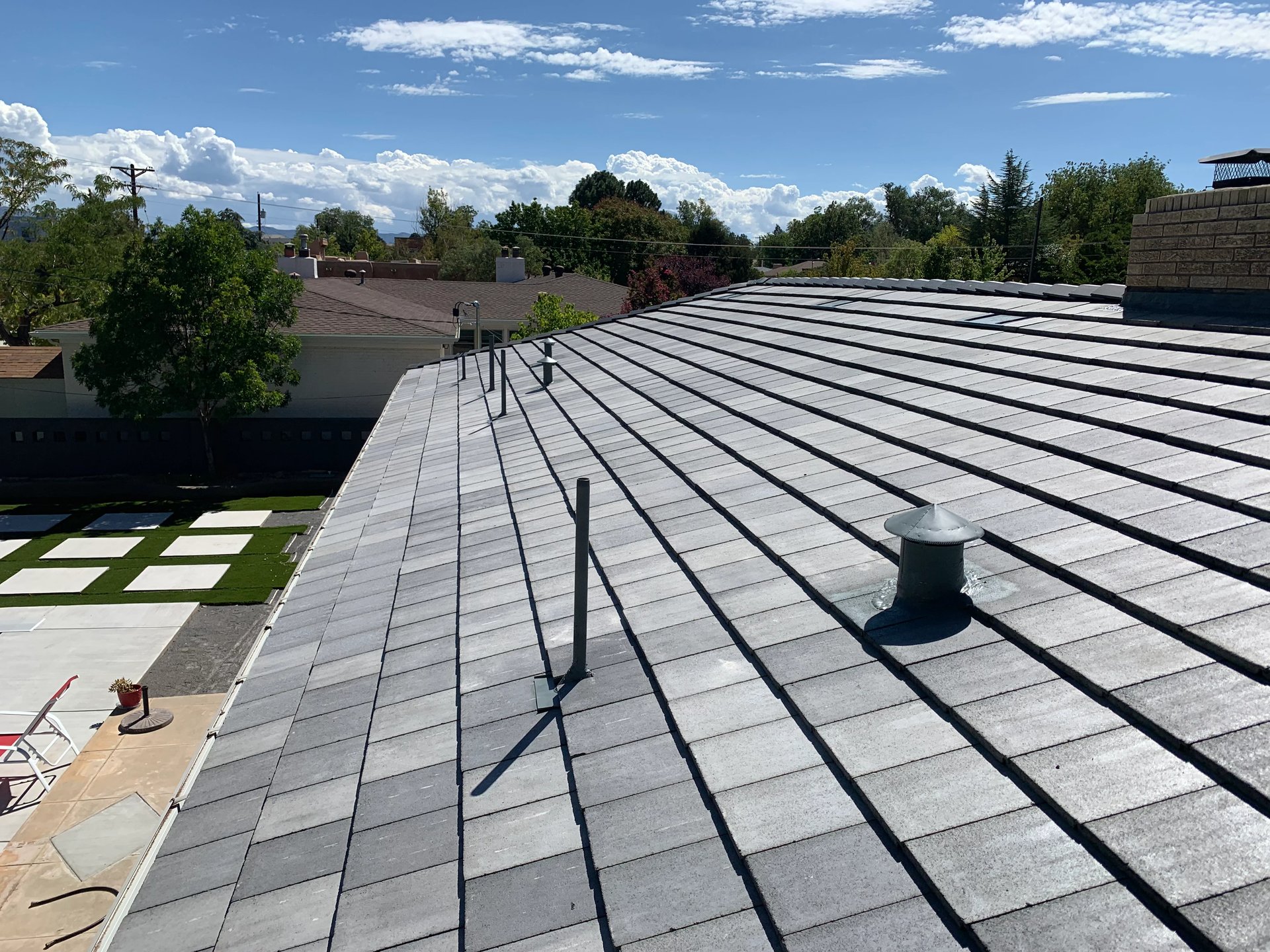 Low-slope shingle roof under a blue New Mexico sky